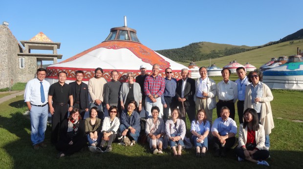 A group of people standing in front of a Mongolian hut