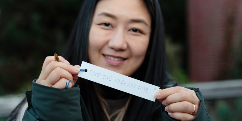 Hwang Sooyoung holding up her wish on a piece of paper: End the Korean War