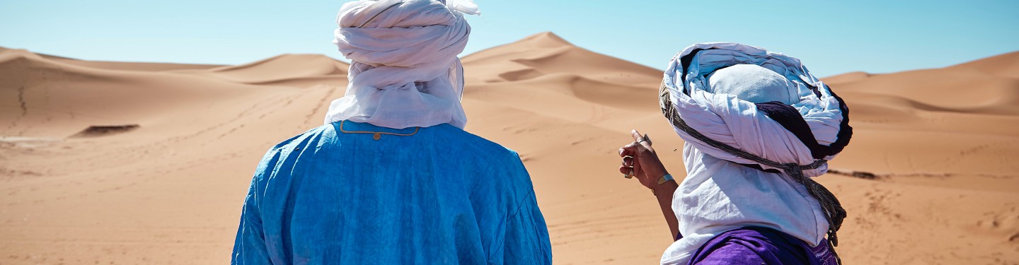 Two men standing in the dessert pointing at the horizon