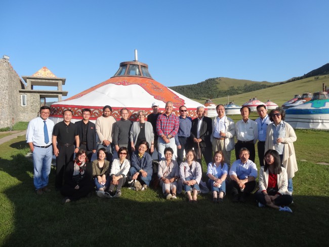 A group of people standing in front of a Mongolian hut