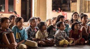 Children following a class while sitting on the floor